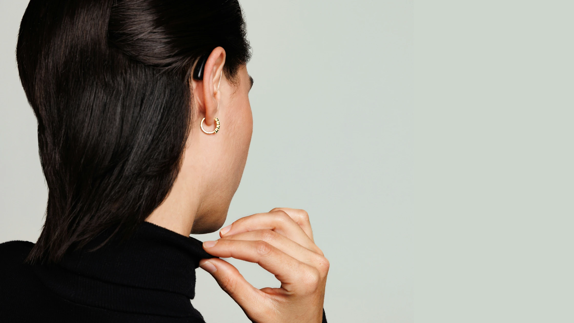 Eine Frau trägt ein modernes Hörsystem hinter dem Ohr.