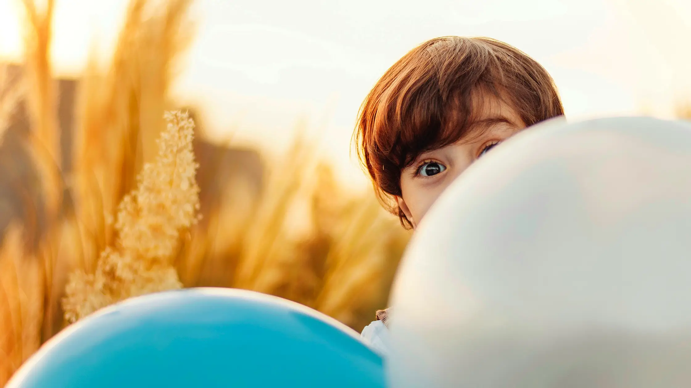 Ein glückliches Kind spielt mit einem Ballon in der Natur.