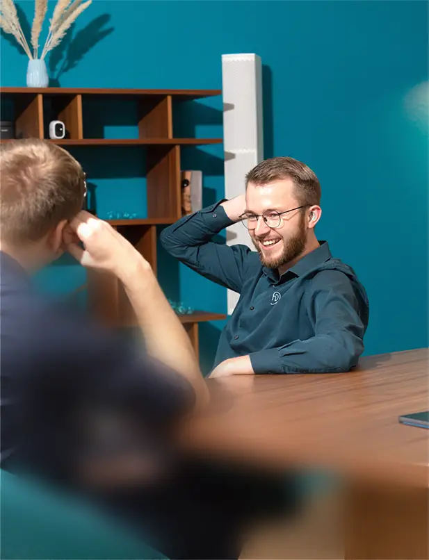 Ein Mitarbeiter von Hörstil lacht, während er sich mit einem Kollegen unterhält.
